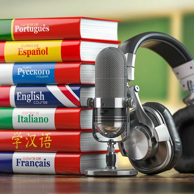 Wörterbücher verschiedener Sprachen mit Kopfhörern und Mikrofon.